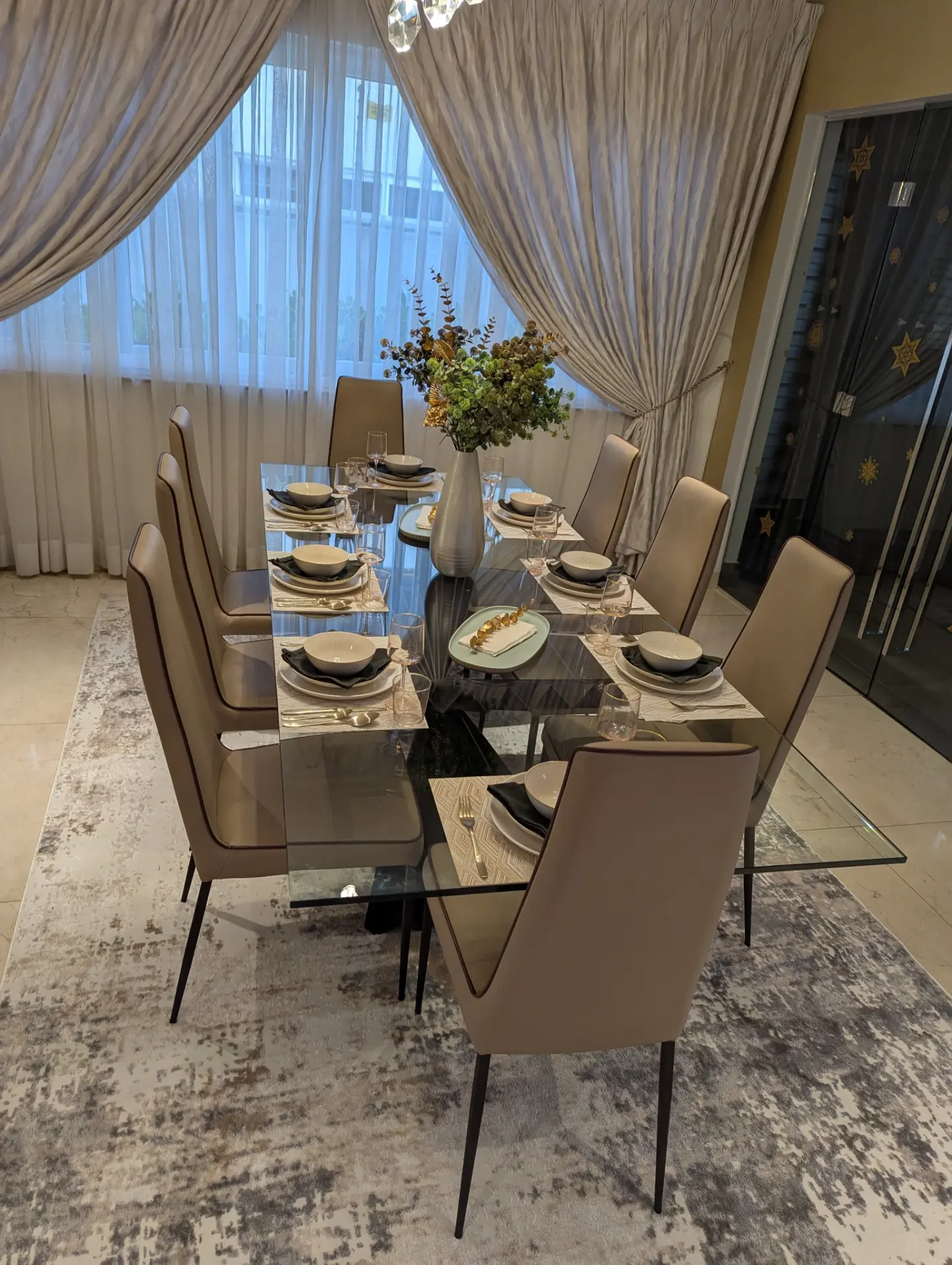 Dining room with glass-top table and tall upholstered chairs